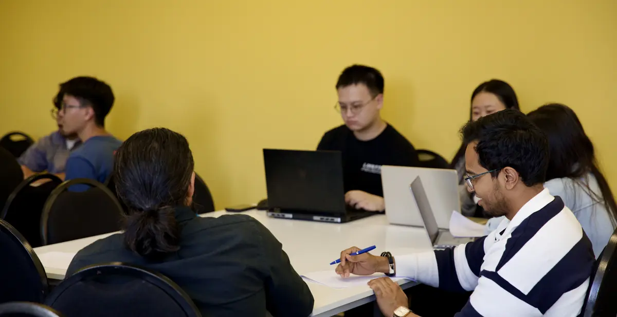 College students working through a money exercise on a laptop together