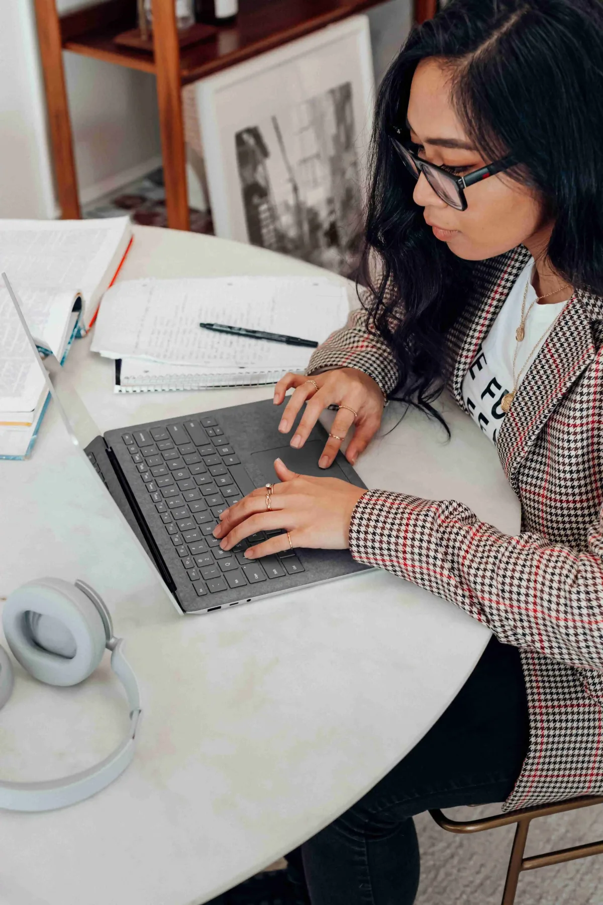 A student typing on a laptop while studying at a desk