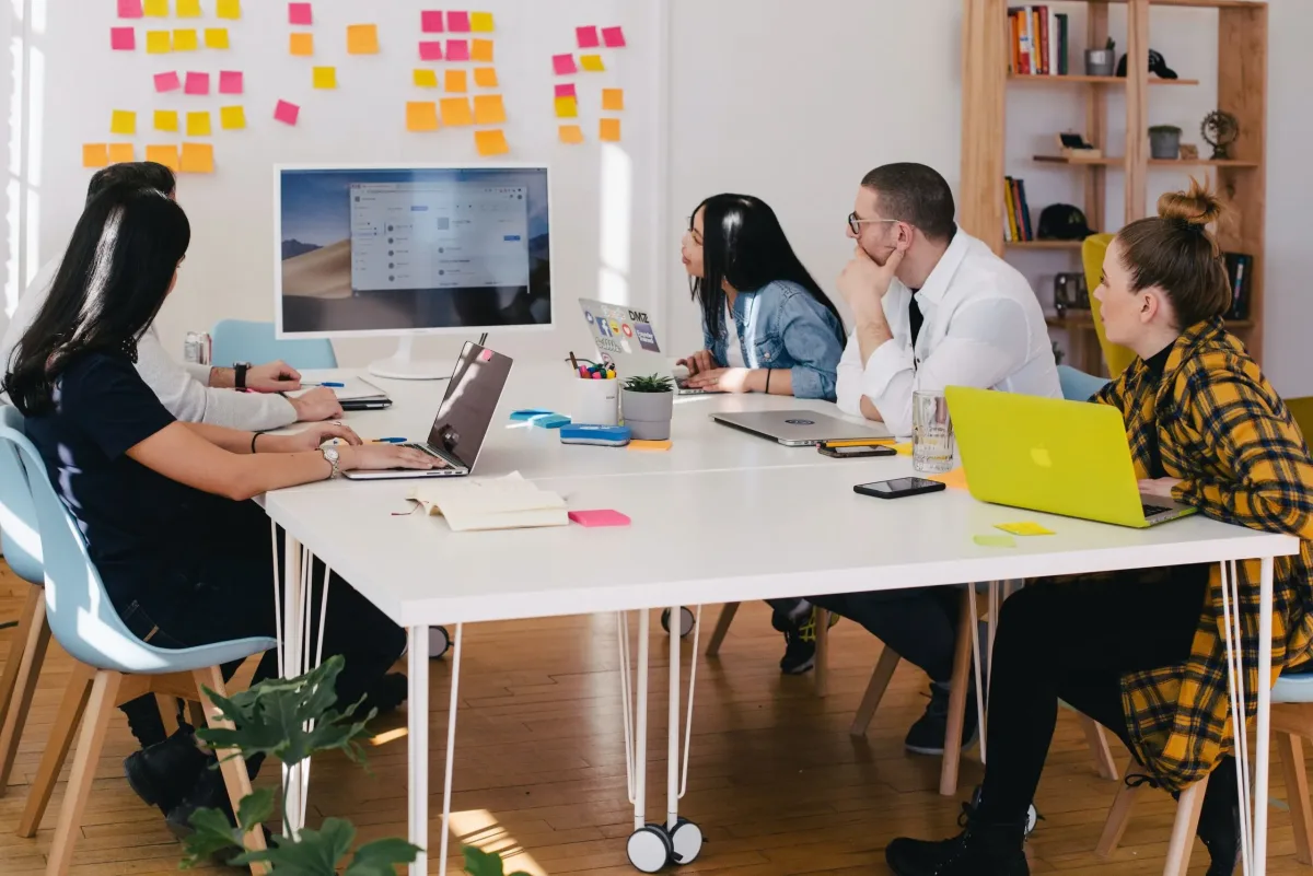 A team meeting around a table with laptops during a workplace financial wellbeing session